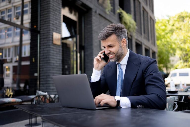 GettyImages 1324748092 Work Design man on phone and laptop scaled e1727232942709